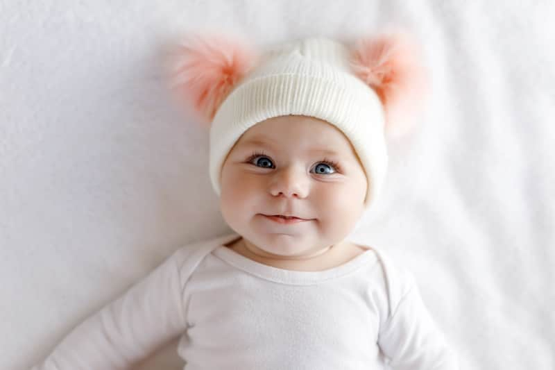 Bébé avec un bonnet à pompons roses