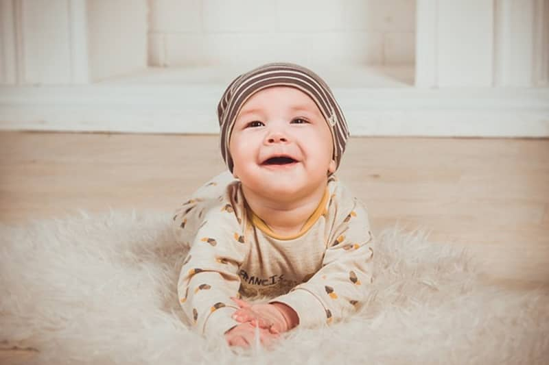 Bébé avec un bonnet allongé sur un tapis