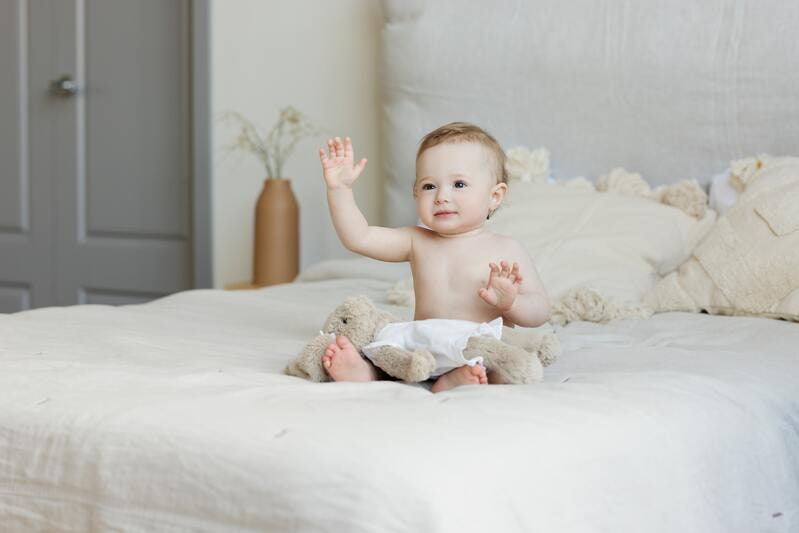 Photo de bébé 9 mois assit sur lit