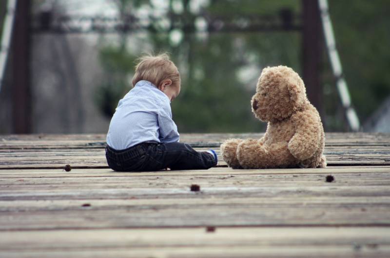 Bébé de 13 mois assis face à son ours en peluche