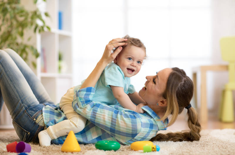 Mère et fils heureux, allongés sur le sol et jouant à l'intérieur