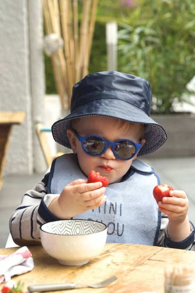 Bébé de 13 mois avec un bob mangeant des fraises